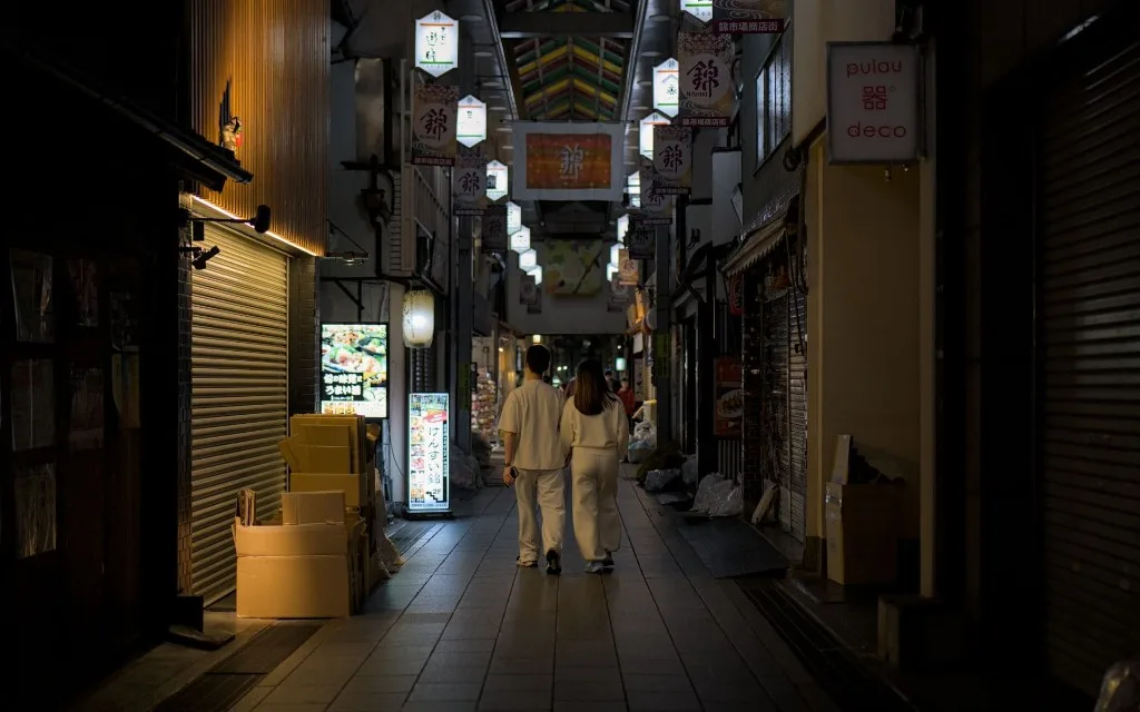 Nishiki Market in Kyoto, Japan at night — a couple walks through the covered shopping arcade