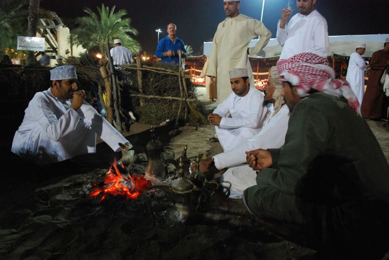 Omani men sharing traditional kahwa coffee around a campfire — cultural experience for families
