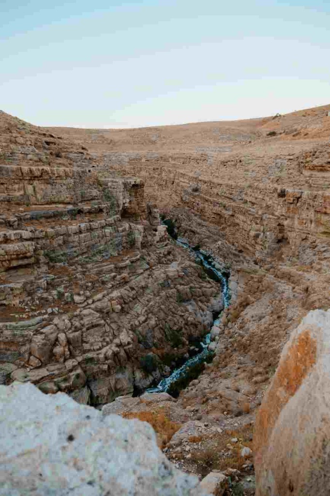 Layered beige canyon with a narrow stream between the rock walls