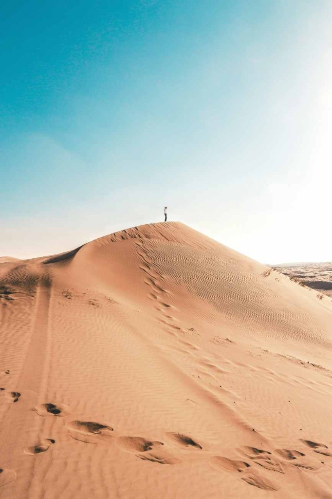 Wahiba Sands dune with a person standing on the crest and footprints in the sand