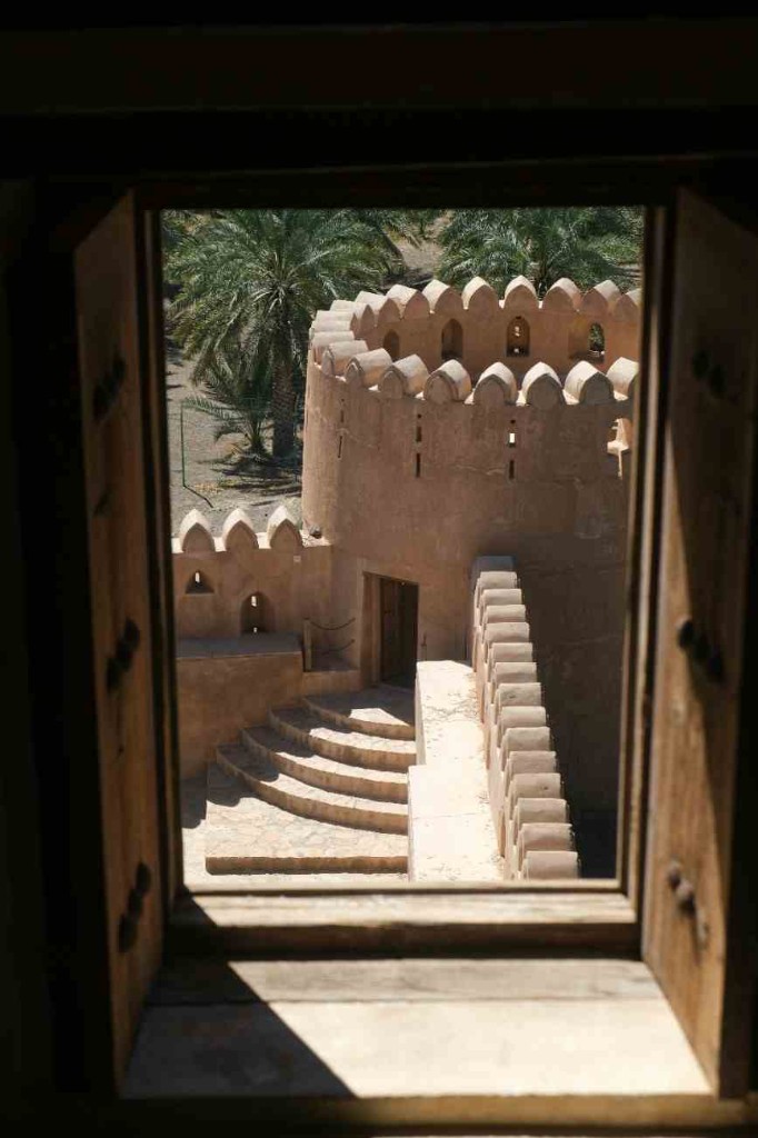 Round tower of an Omani fort seen through a wooden window, the view on a Nizwa day from Muscat