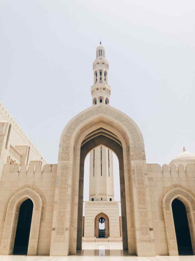 Sultan Qaboos Grand Mosque minaret framed by a carved stone arch in Muscat