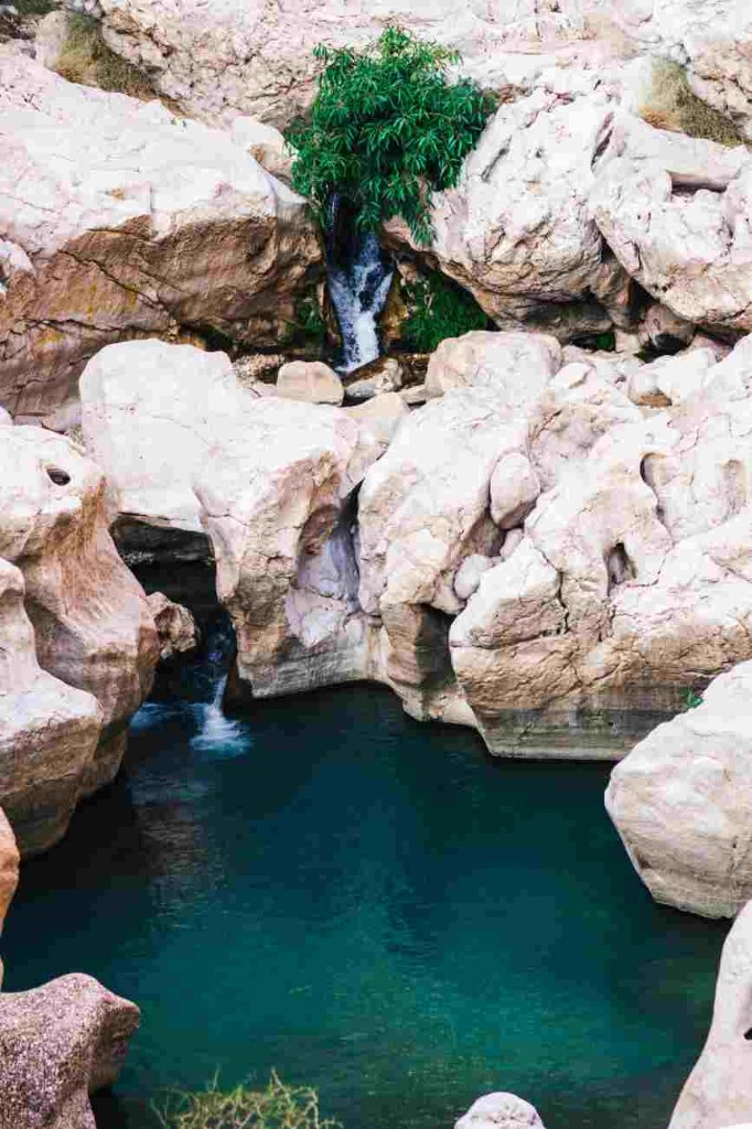 Turquoise pool and small waterfall in the white rock of Wadi Shab on a day trip from Muscat
