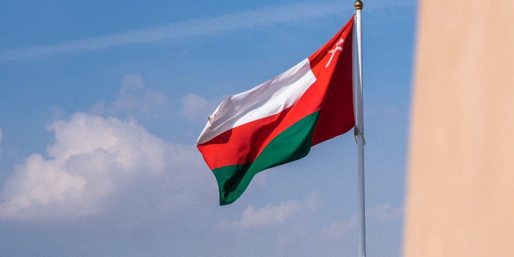 Oman national flag waving against blue sky in Muscat