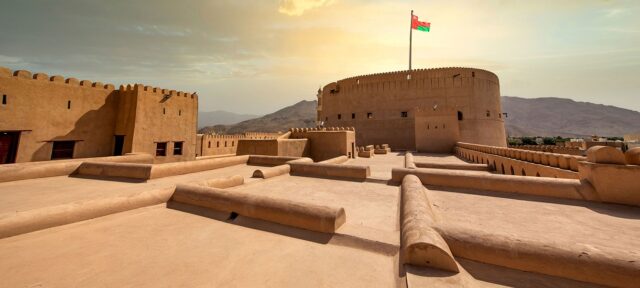 Nizwa city tour in Oman featuring Nizwa Fort, traditional souq market, and historic architecture with Hajar Mountains in the background